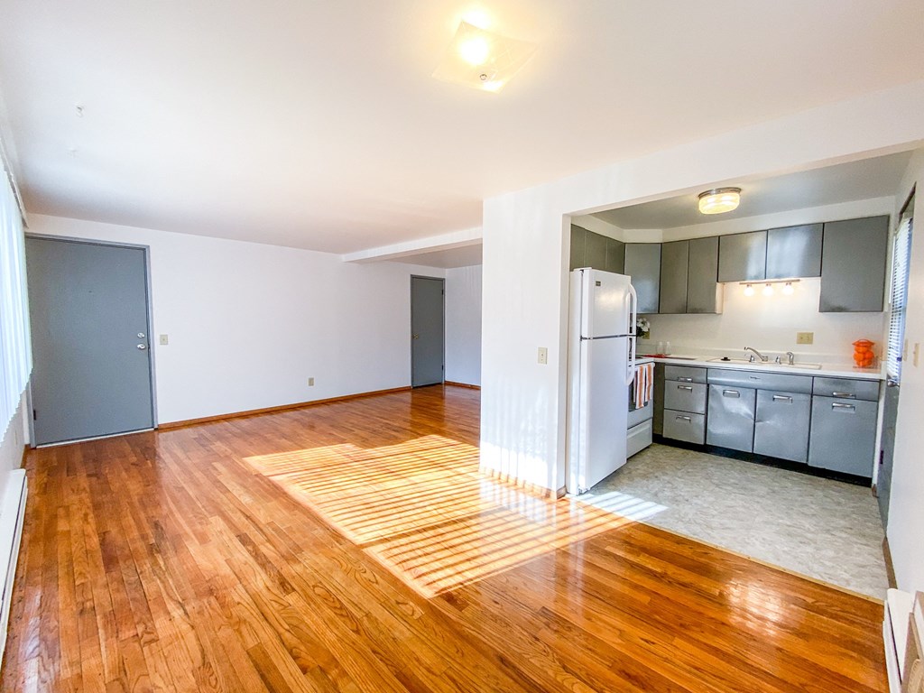 an empty living room and kitchen with a hard wood floor
