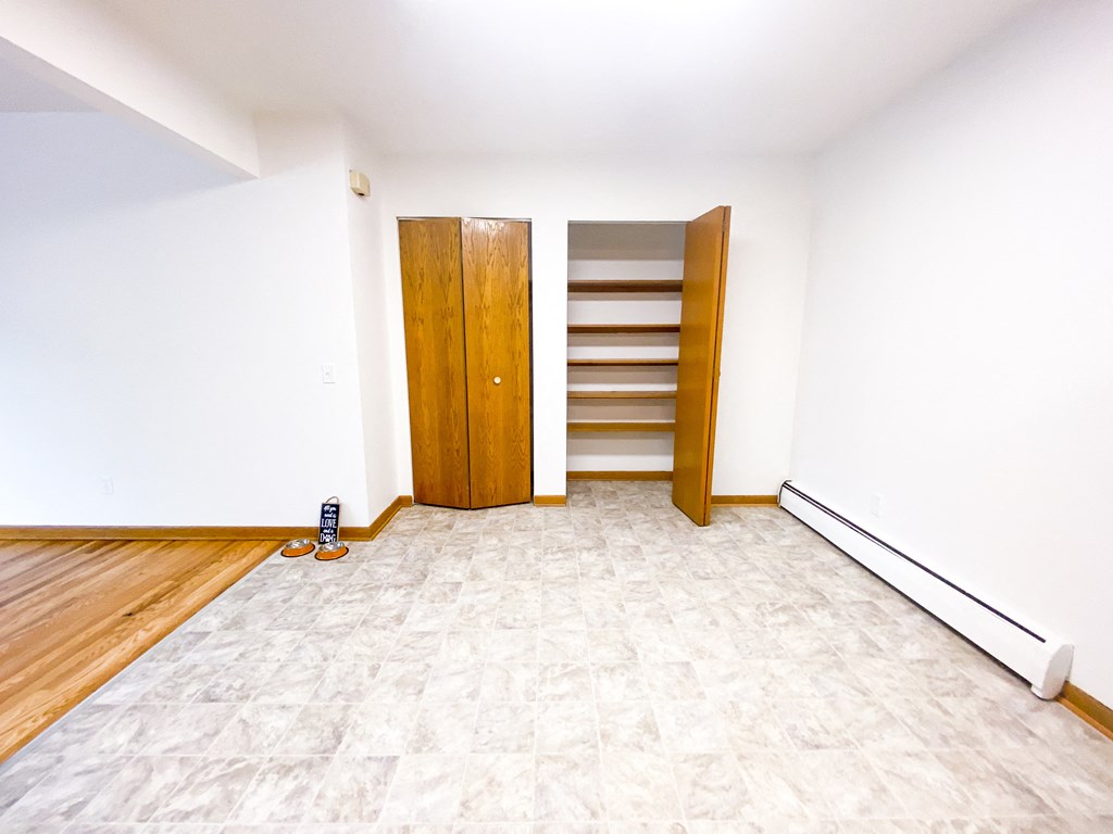 an empty room with white walls and wooden floors and a wooden door