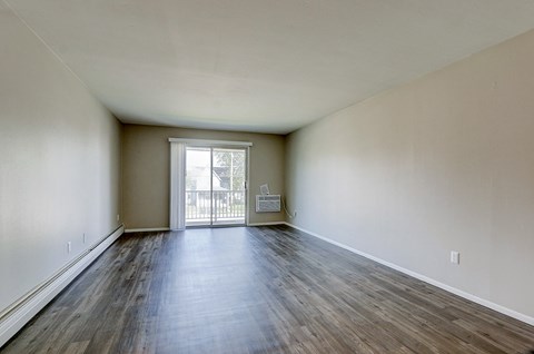 A room with wooden floors and a sliding glass door leading to a balcony.
