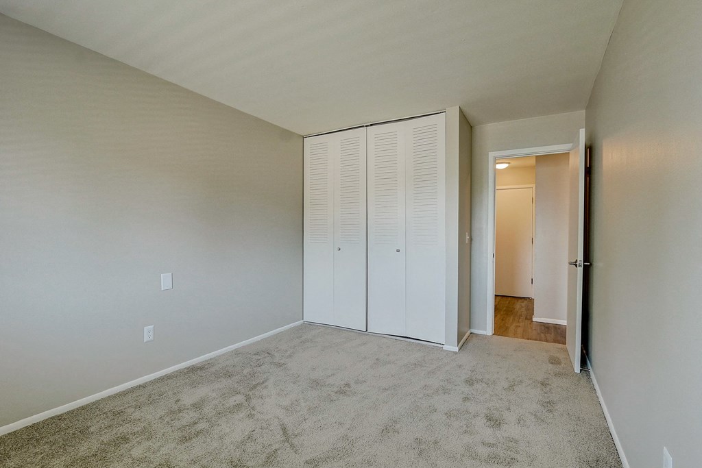 an empty bedroom with white closet doors on the wall