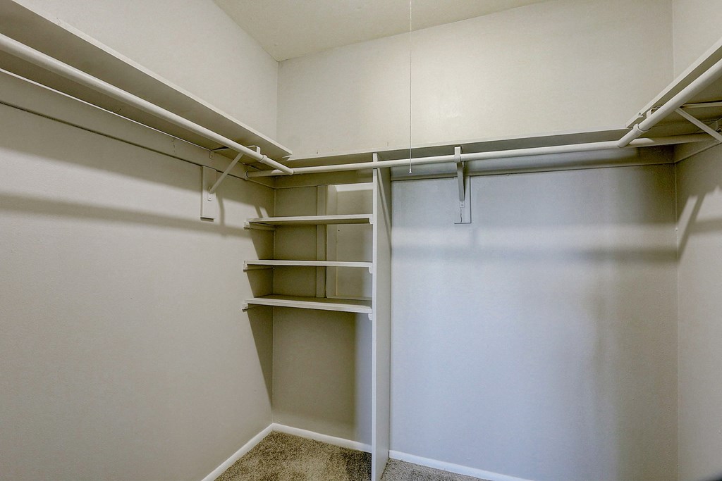 a walk in closet with empty shelves and a sliding closet door