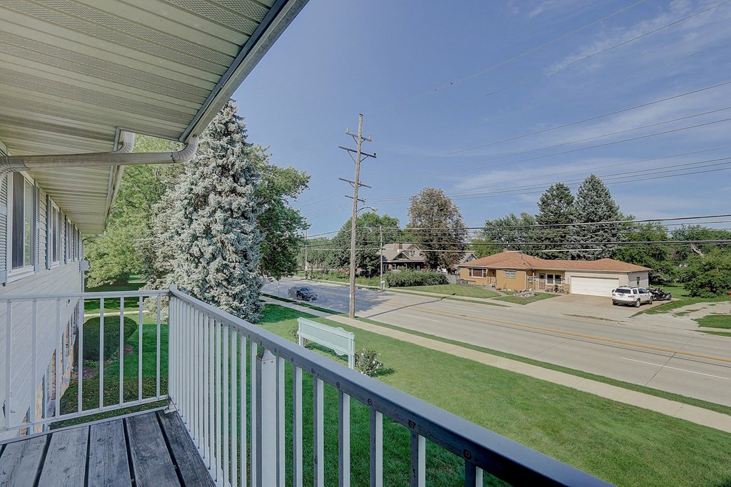 the view from the deck of a house overlooking a street and trees