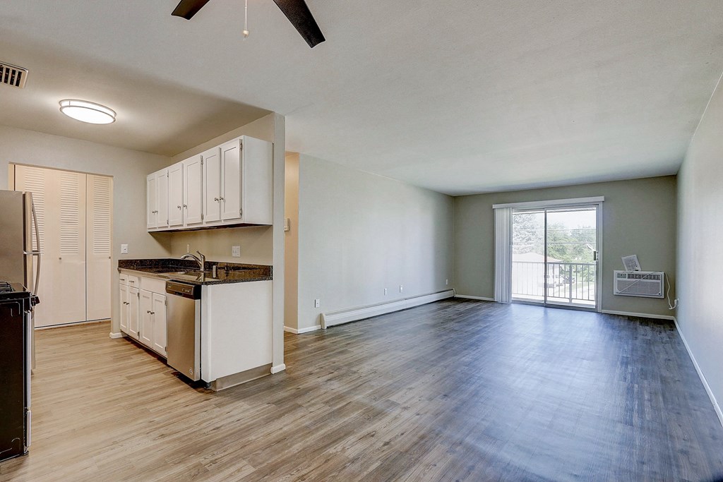 an empty kitchen and living room with a door to a balcony