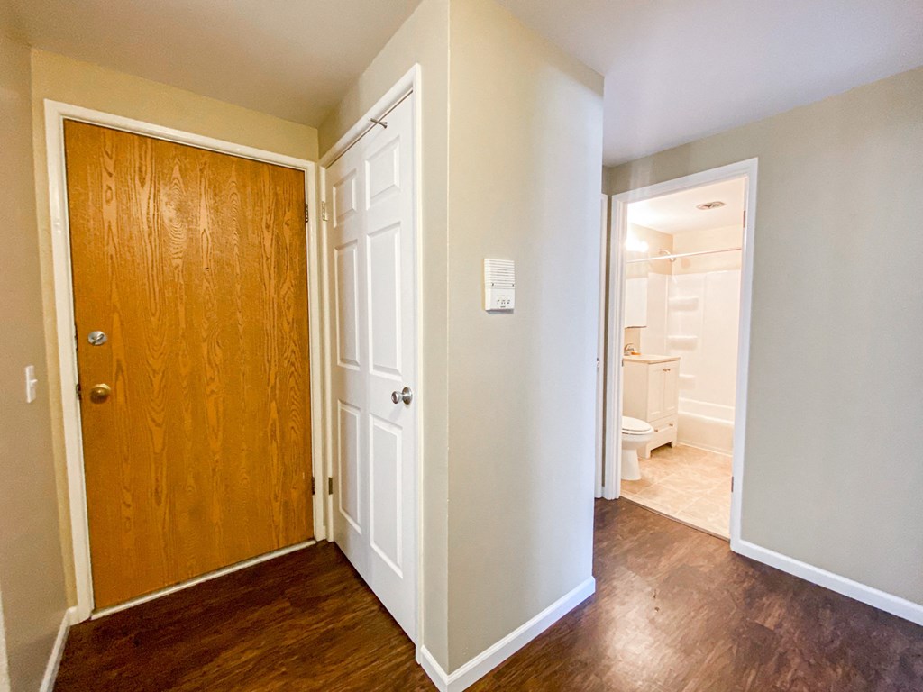 an empty room with a wooden door and a hallway to a bathroom