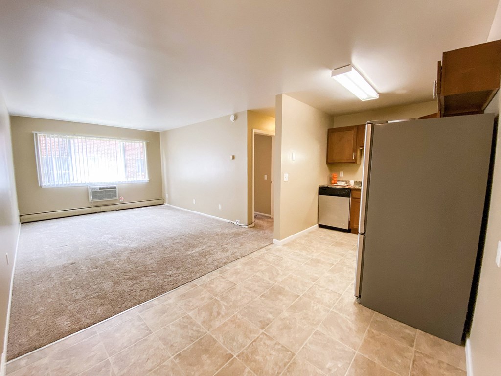 an empty living room and kitchen with a refrigerator