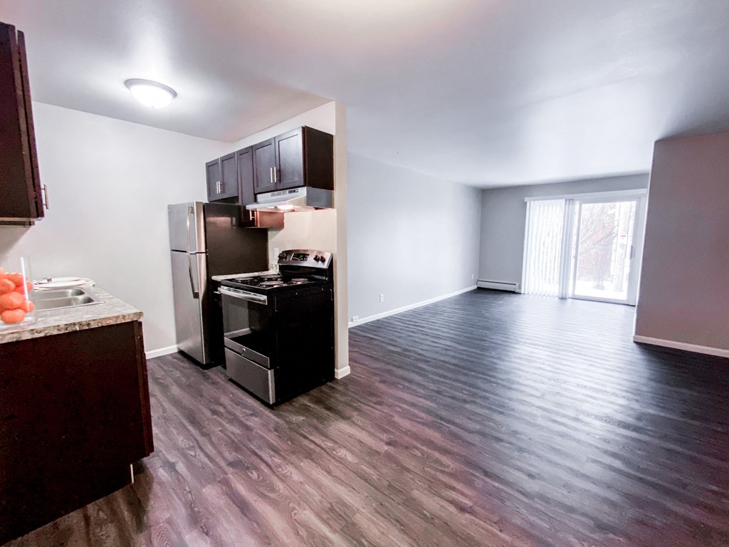 an empty living room and kitchen with wood flooring and