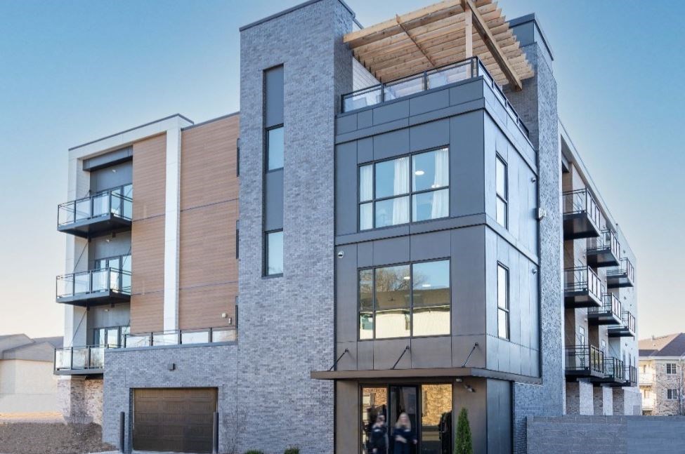 A modern multi-story building with balconies and a wooden roof.