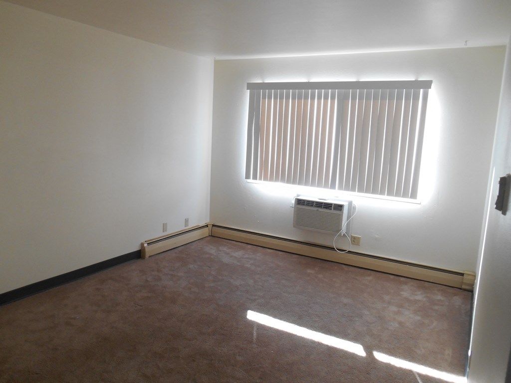 an empty room with a window and an air conditioner