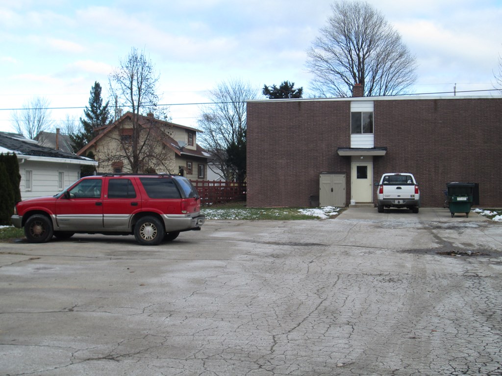 a red suv parked in a parking lot in front of a brick house