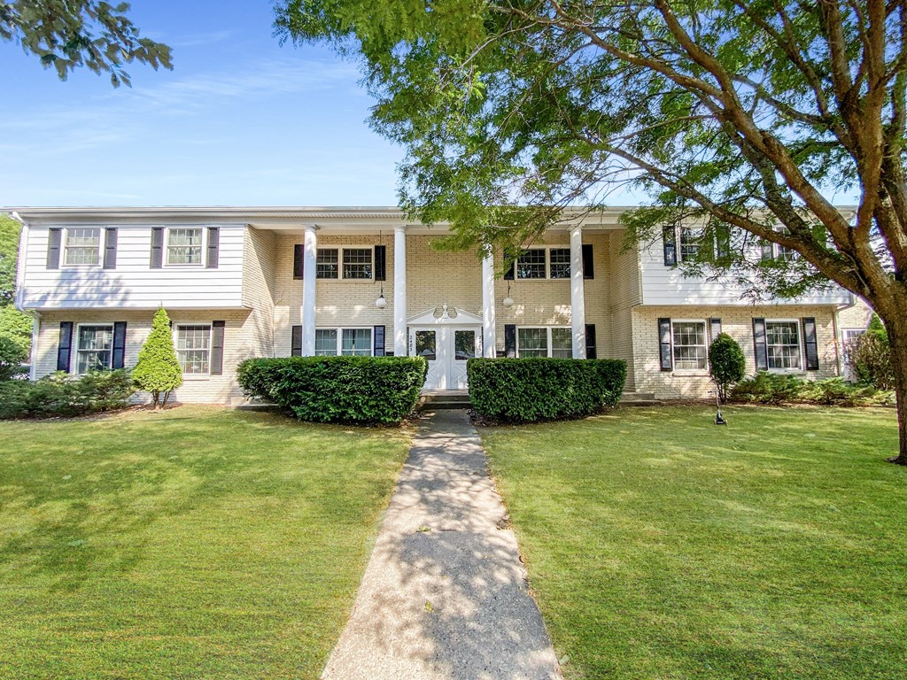 a white house with a lawn and trees in front of it