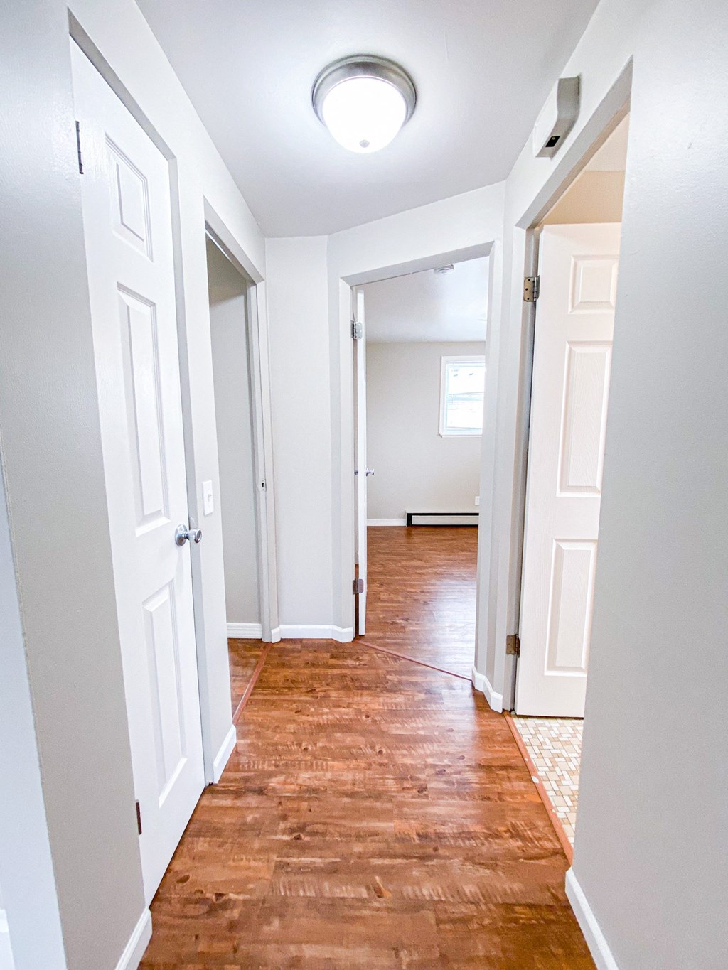 an empty hallway with white doors and a wood floor