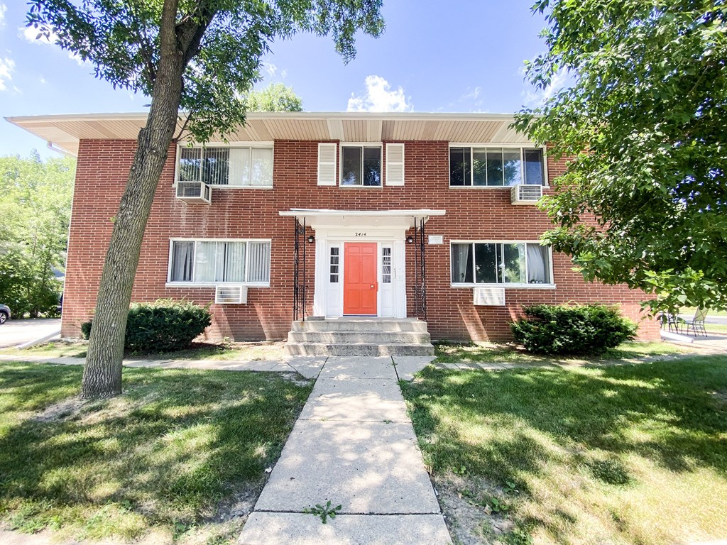 the front of a brick house with a red door