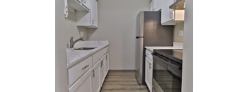 an empty kitchen with white cabinets and stainless steel appliances
