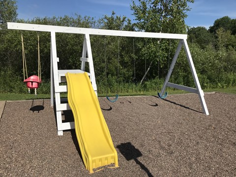 A playground with a yellow slide and a red ball.