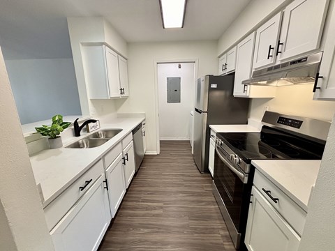 A kitchen with white cabinets and a black fridge.