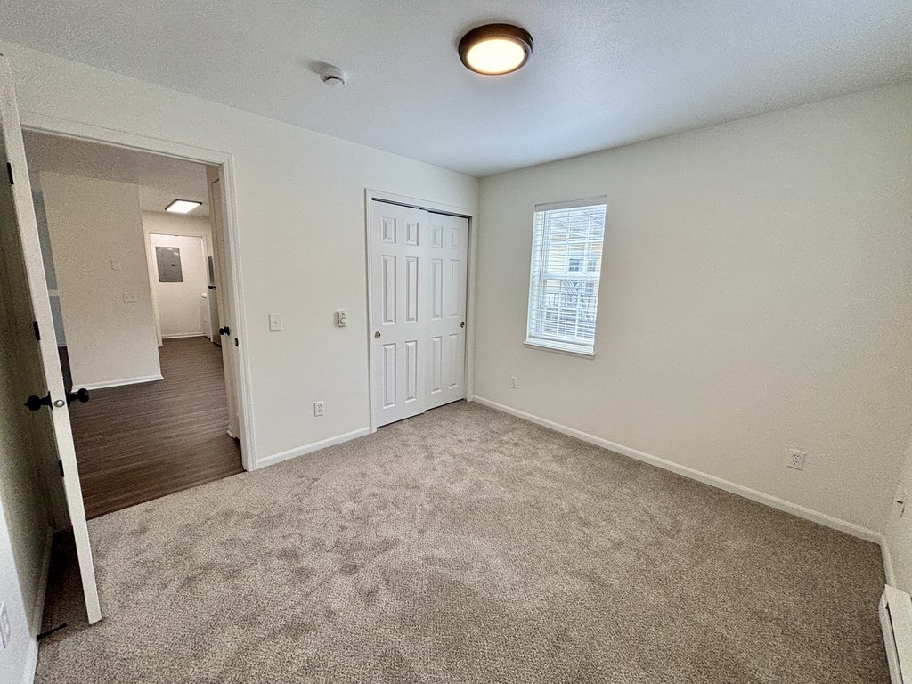 A room with a carpeted floor and a door leading to another room.