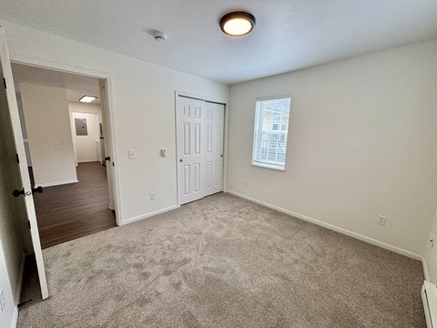 A room with a carpeted floor and a door leading to another room.