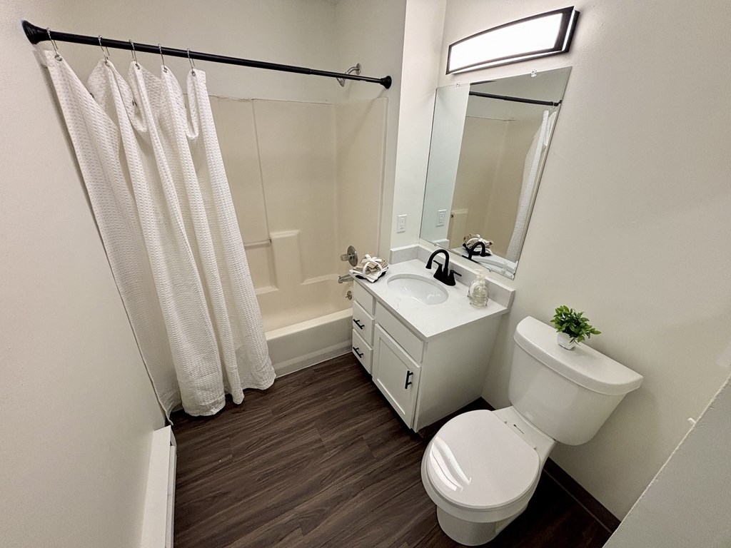 A white bathroom with a toilet, sink, and shower.