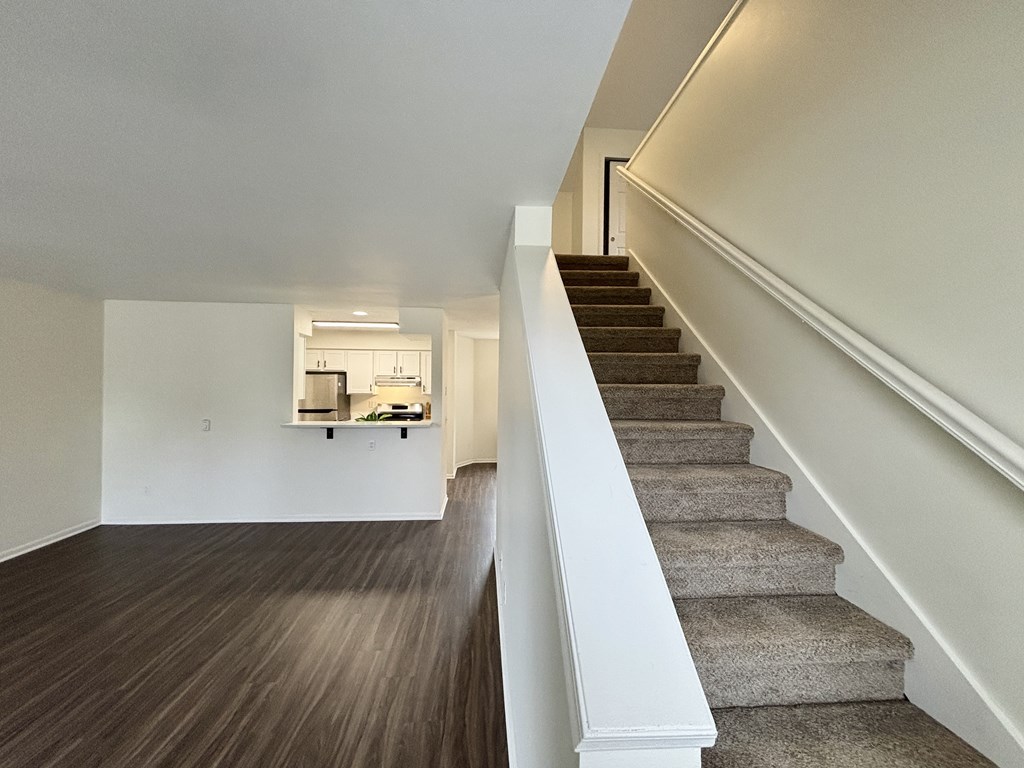 A staircase with a white railing and a brown carpeted runner.