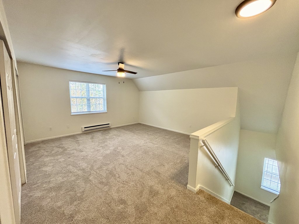 A room with a carpeted floor and a window with blinds.