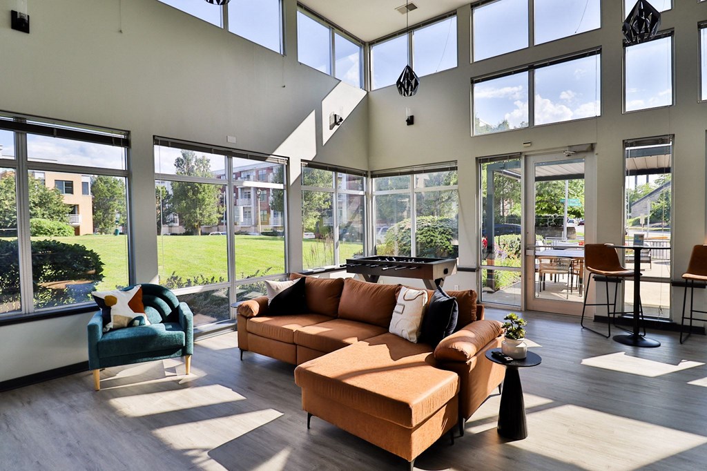a living room with a couch and chairs and large windows