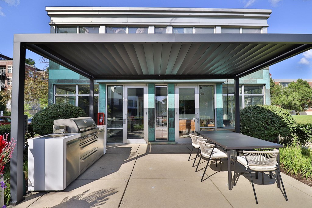 a patio with a barbecue grill and a table and chairs