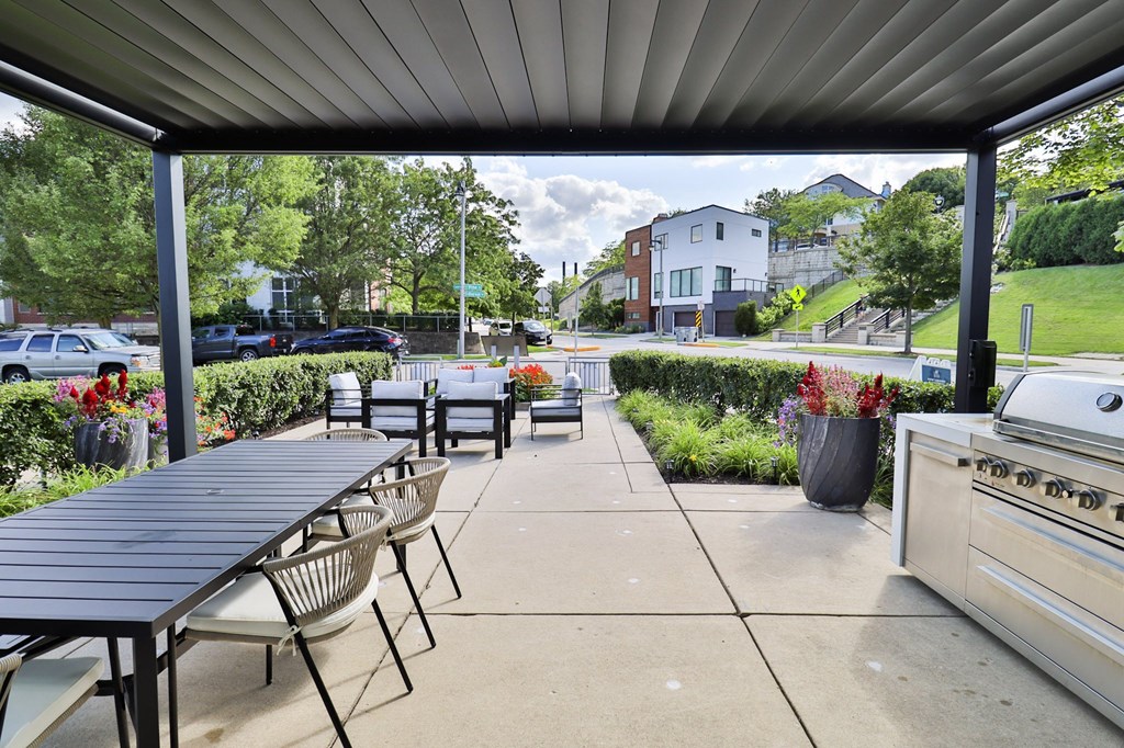a patio with a table and chairs and a grill