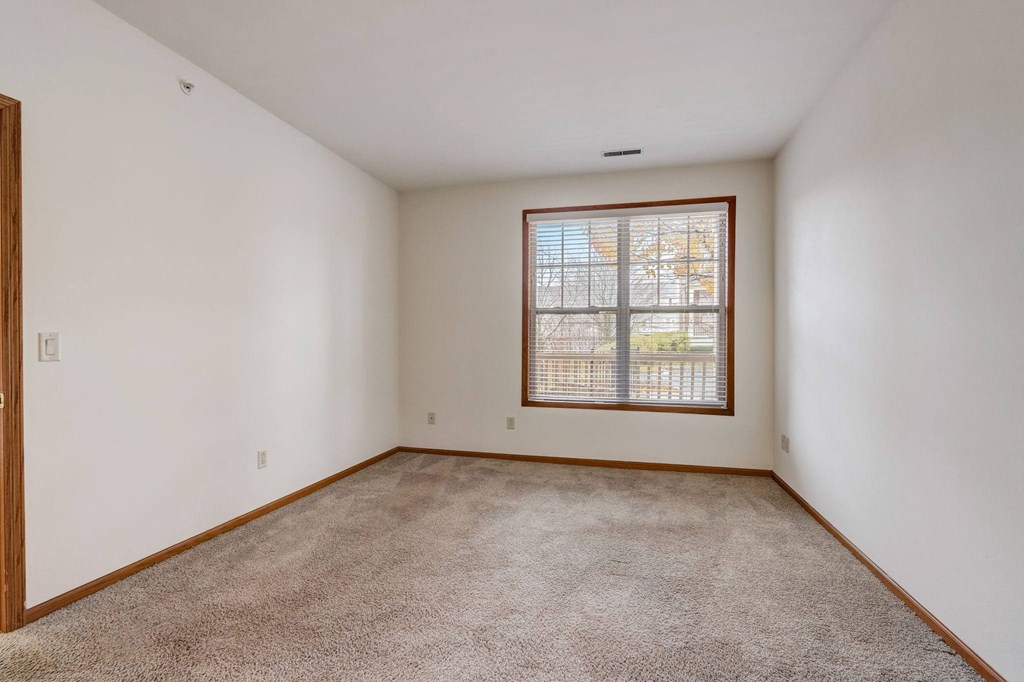 an empty living room with a window and carpet