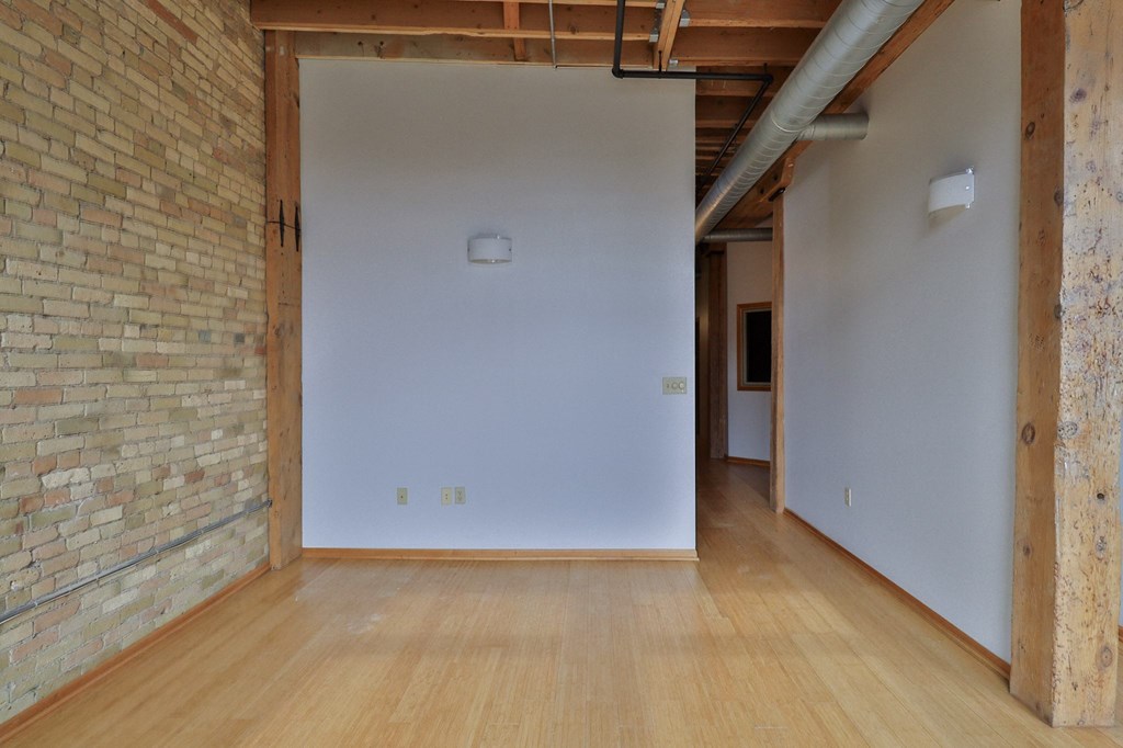 an empty room with a white wall and wood floors