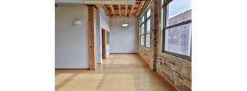a hallway with large windows and wood floors and a ceiling light