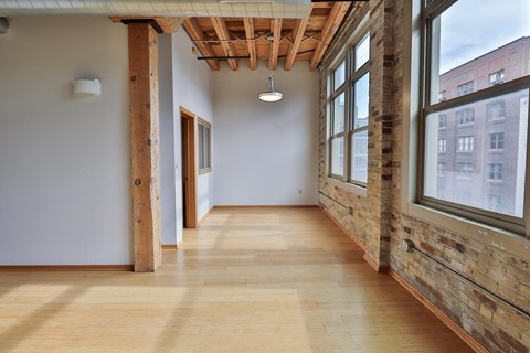 a hallway with large windows and wood floors and a ceiling light