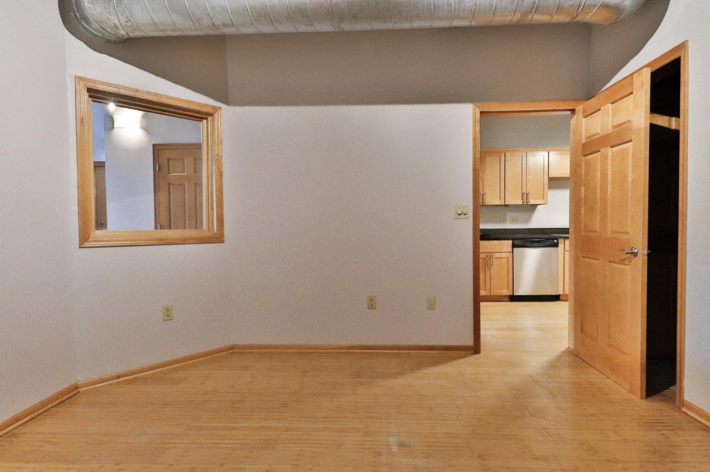 an empty living room with a door to a kitchen
