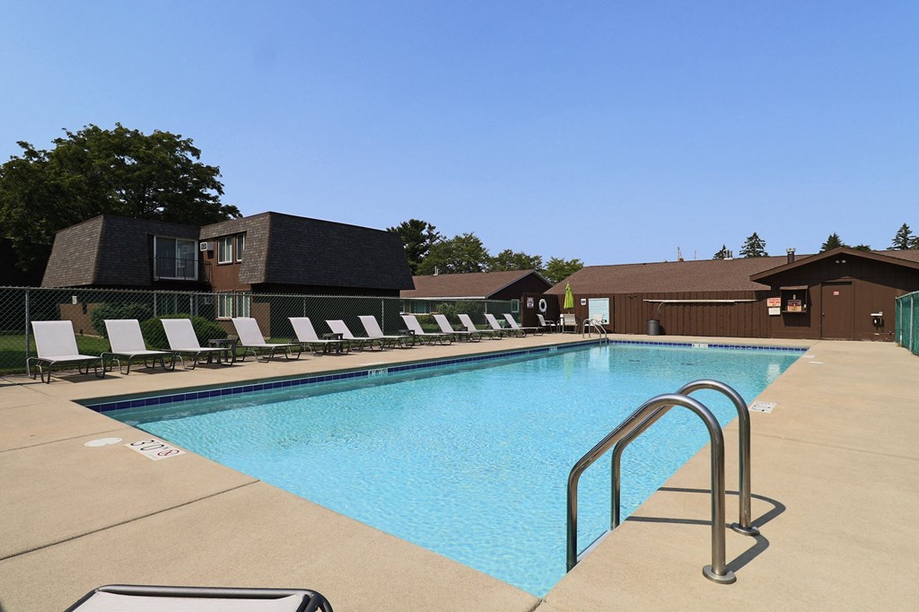 a swimming pool with chairs around it in front of a building