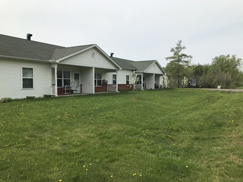 A white house with a grey roof and a green lawn in front.