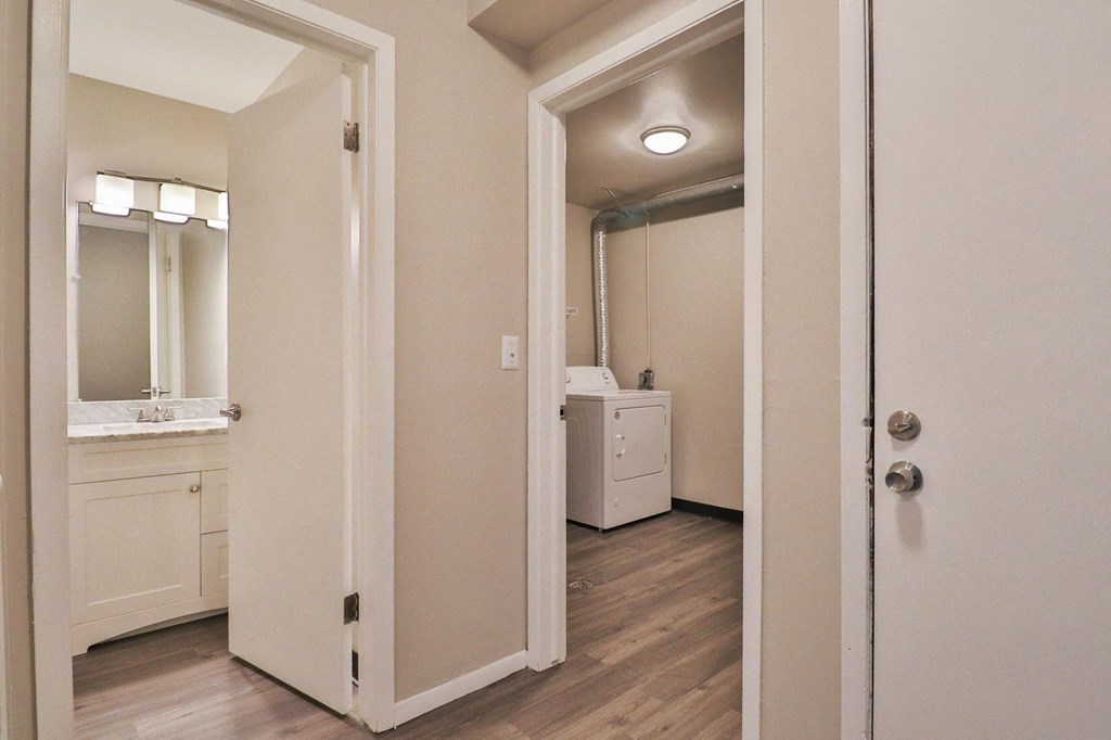 a bedroom with a door open to a bathroom with a sink and a mirror