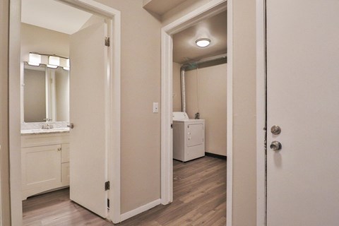 a bedroom with a door open to a bathroom with a sink and a mirror