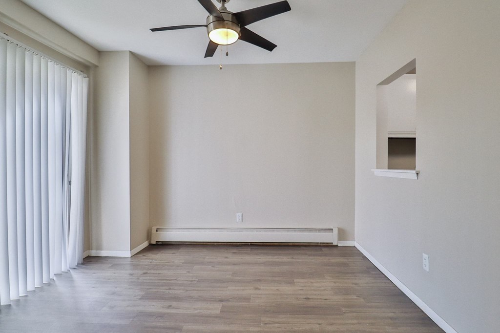 an empty living room with white walls and a ceiling fan