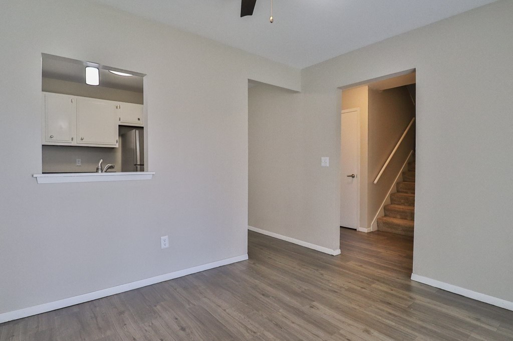 the living room and kitchen of an empty apartment with wood flooring
