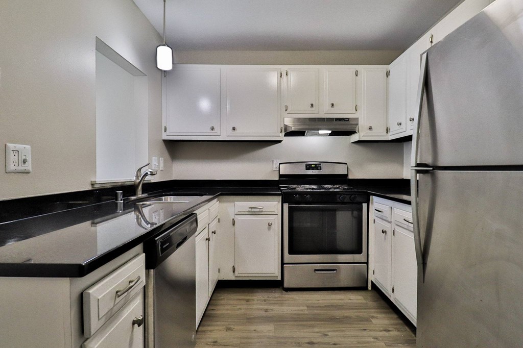 an empty kitchen with stainless steel appliances and white cabinets