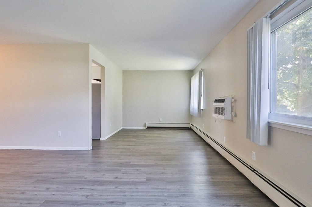 an empty living room with wood flooring and large windows