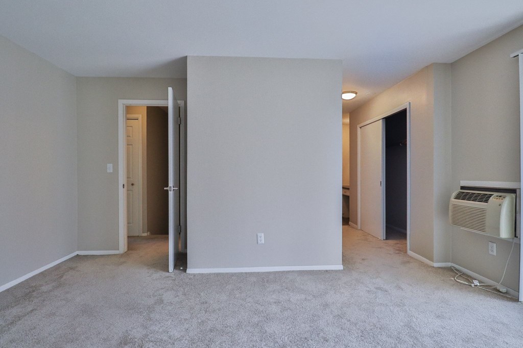 an empty living room with an open door to a bedroom