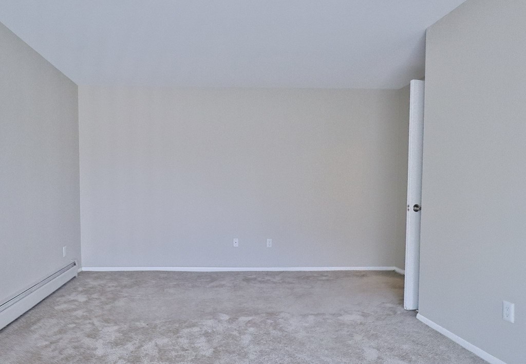 an empty room with white walls and carpet
