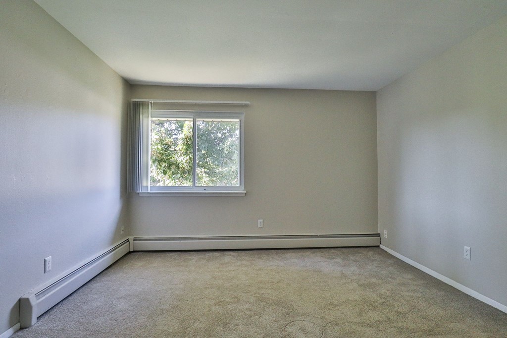 an empty room with a window and white walls