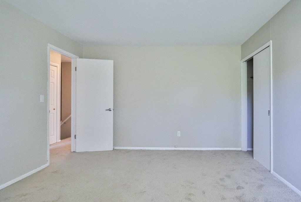 an empty room with white walls and a door to a closet