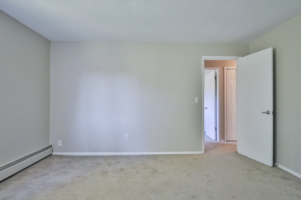an empty living room with white walls and a door to a hallway