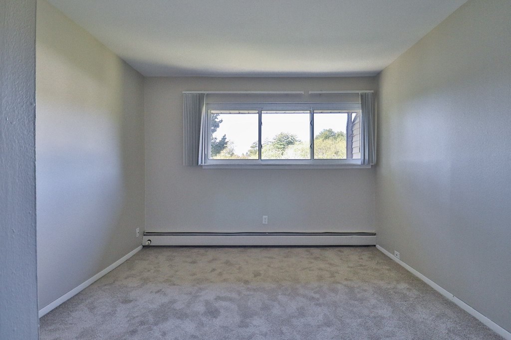 an empty room with a window and white walls