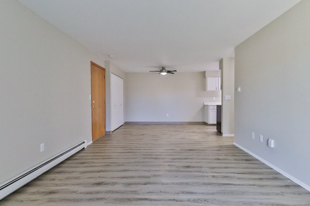 an empty living room with wood flooring and a ceiling fan