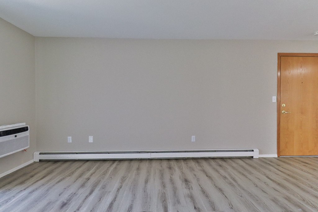 an empty living room with wood floors and a door
