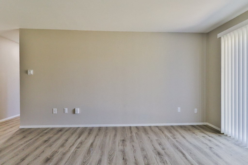 an empty living room with wood floors and white walls