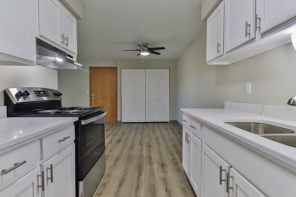 an empty kitchen with white cabinets and a ceiling fan
